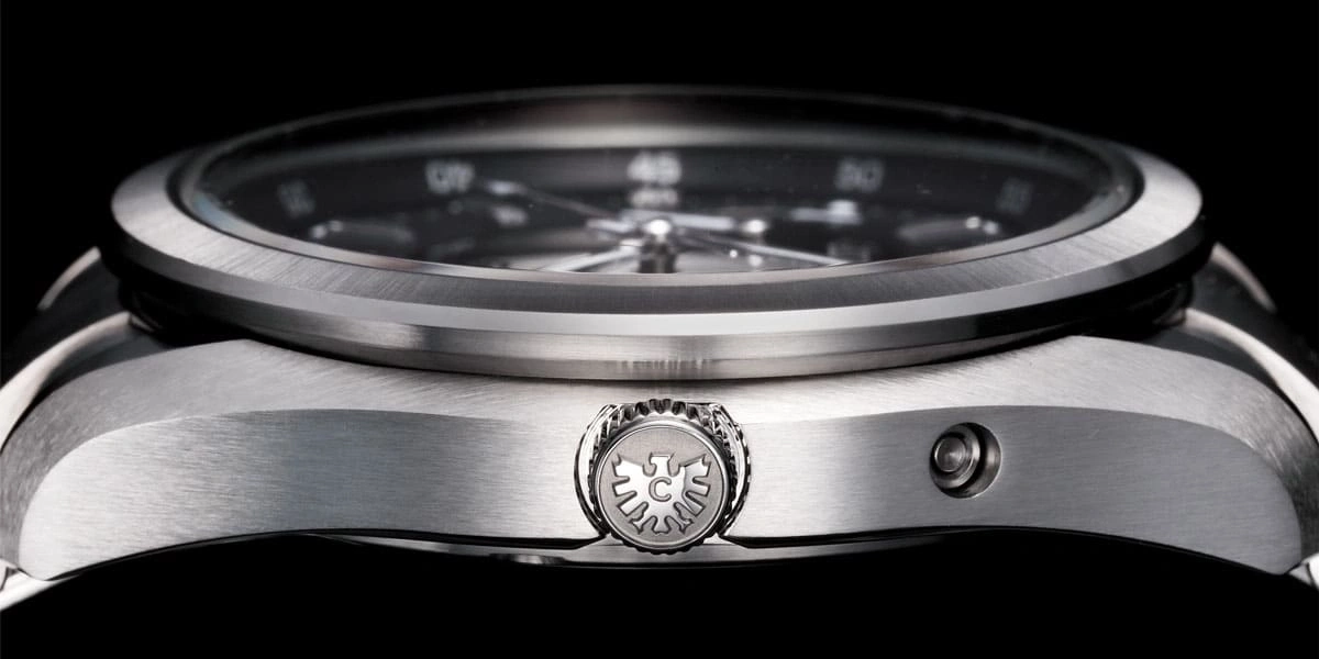 Close-up van een zilveren horloge met een zwarte wijzerplaat en ingewikkelde details.