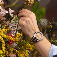 Mannen polshorloge met bloemen. Een persoon schikt bloemen met een horloge om.