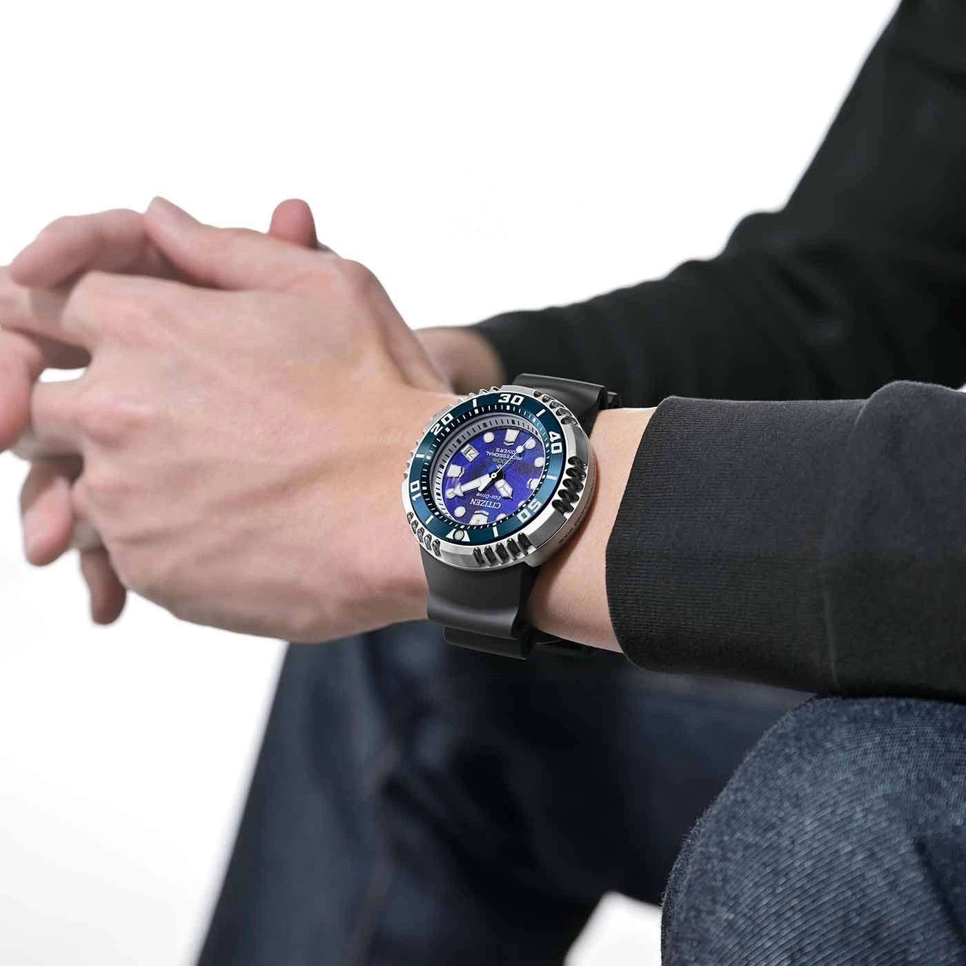 Man draagt Citizen horloge met blauwe wijzerplaat en zwarte band.