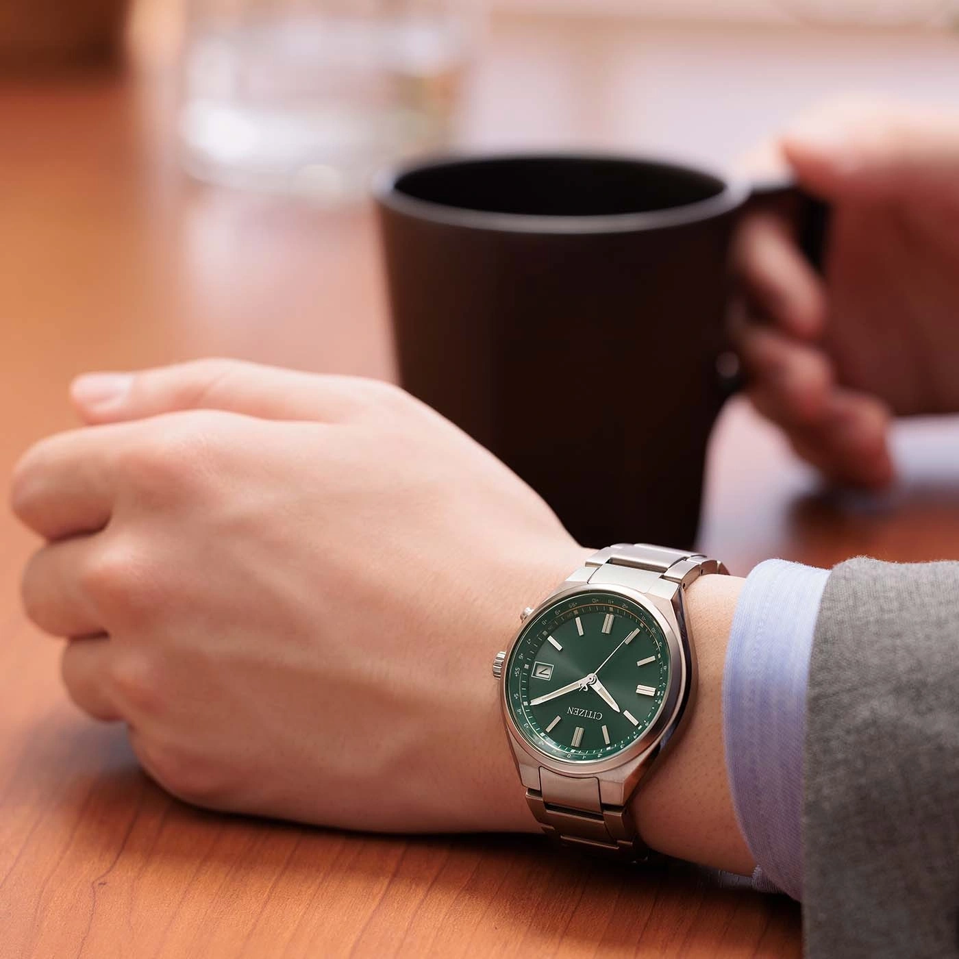 Een persoon met een groen horloge en een mok koffie.