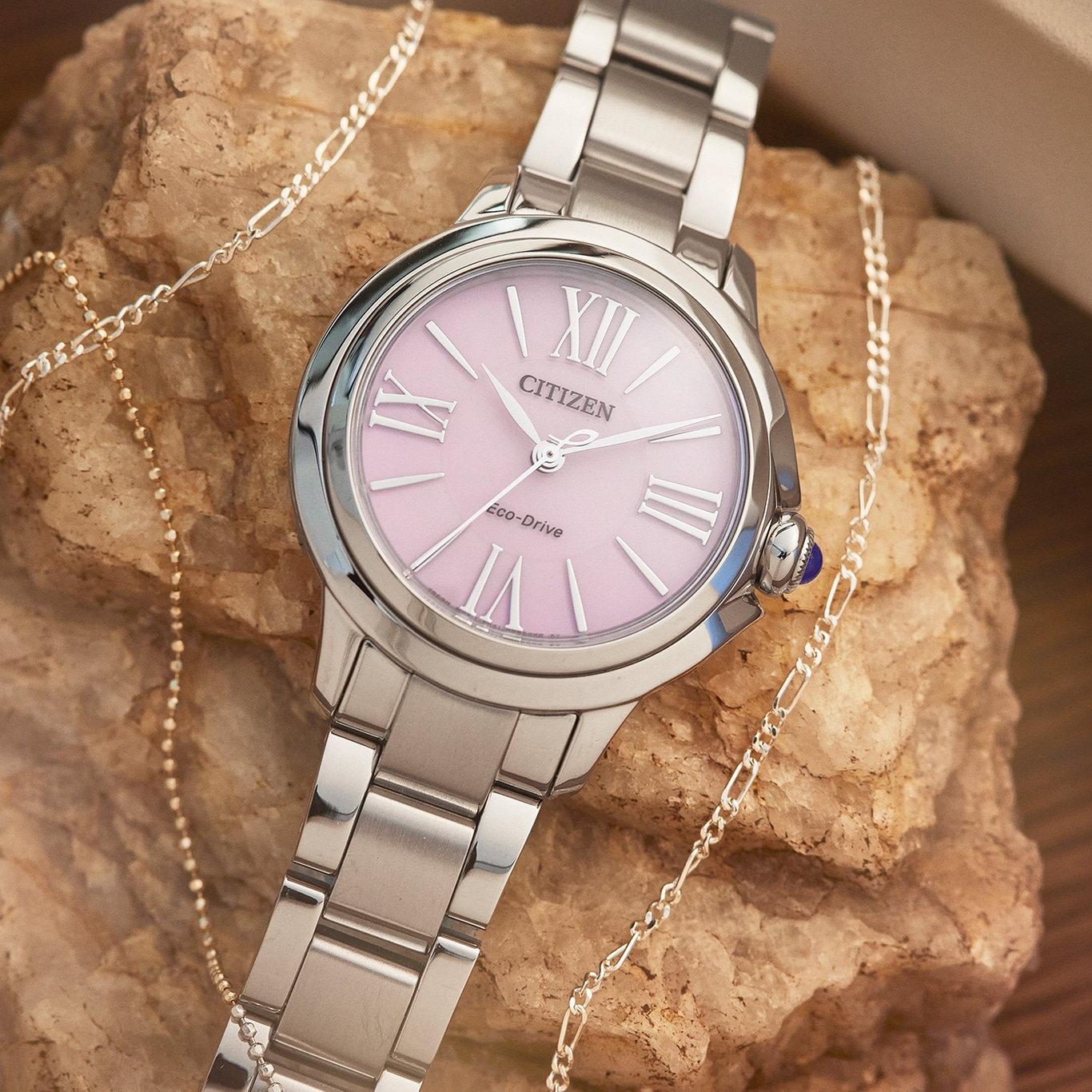 Citizen horloge met roze wijzerplaat en zilveren armband, met sieraden.