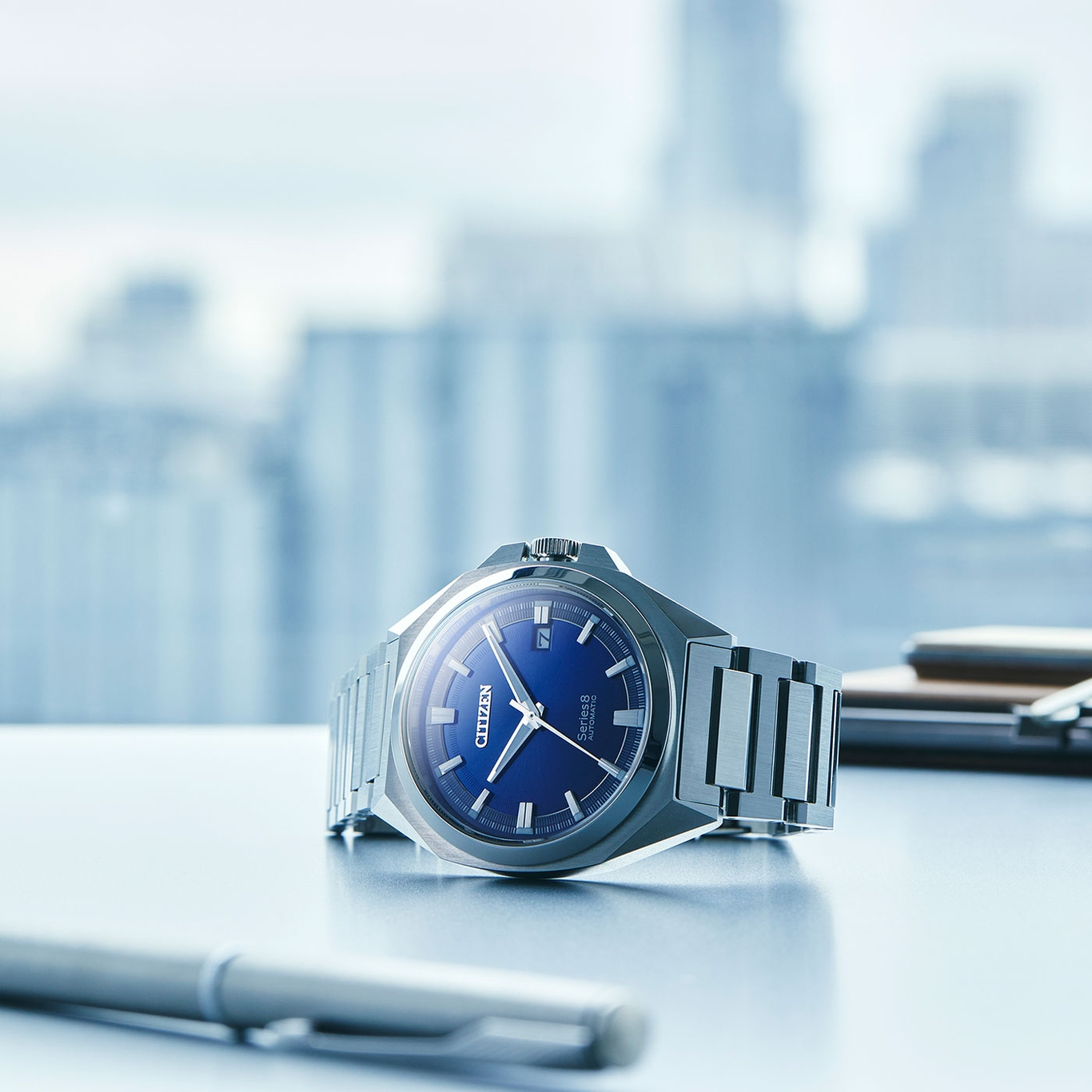 Citizen Series 8 horloge met blauwe wijzerplaat op een bureau met een pen.