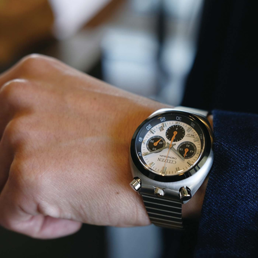 De pols van een man met een zilveren Citizen chronograaf horloge.