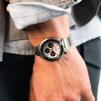 Een man die een zilveren Citizen chronograaf horloge draagt.