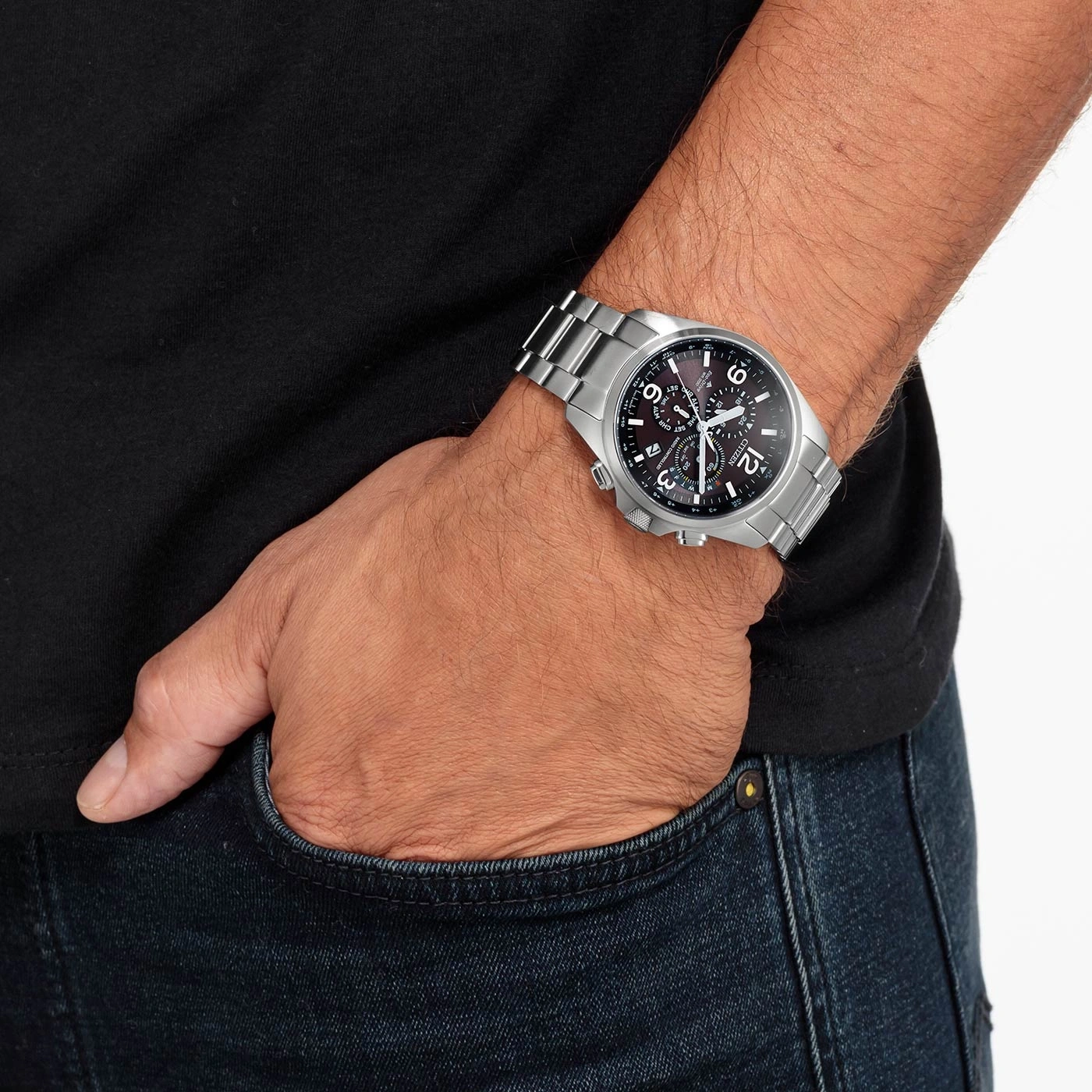 Man met zilveren horloge, zwart shirt en blauwe jeans.