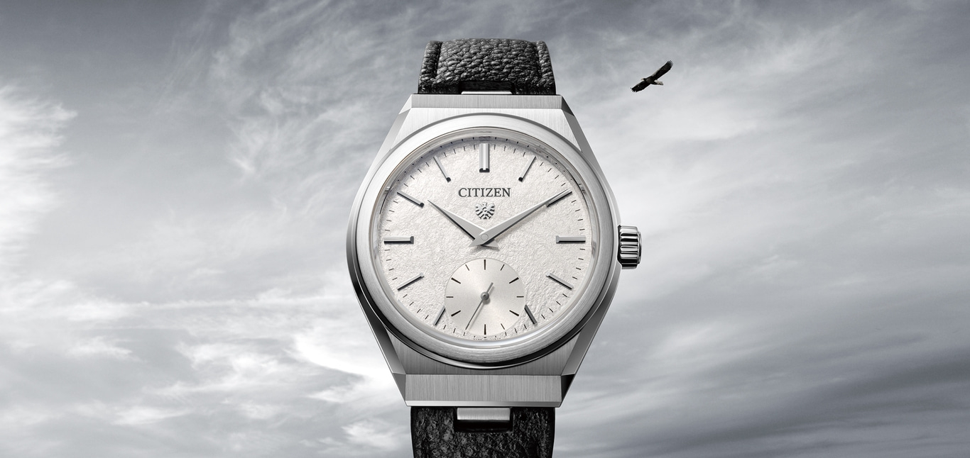 Citizen horloge met een getextureerde wijzerplaat en vogel in de lucht.