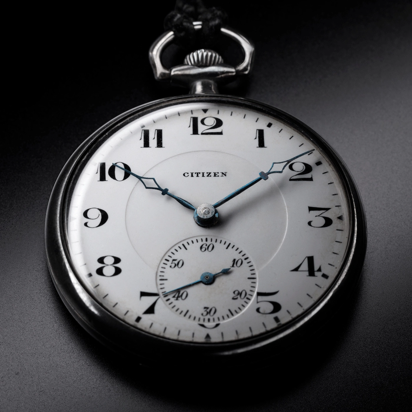 Close-up van een Citizen zakhorloge, met de tijd en details op een zwarte achtergrond.
