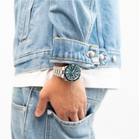 Man draagt een spijkerjack en spijkerbroek met een horloge.