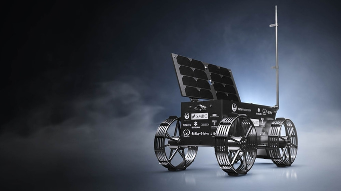 Der Mondrover der HAKUTO-R-Mission mit vier Gitterrädern, Solarpanel und Antenne, steht vor dunklem Hintergrund. Auf dem Gehäuse sind Logos der Partnerunternehmen wie CITIZEN, Suzuki und SMBC gut sichtbar angebracht.