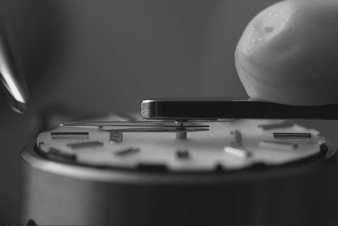 Close-up van horlogemechanisme dat met precisie en gereedschap wordt geassembleerd.