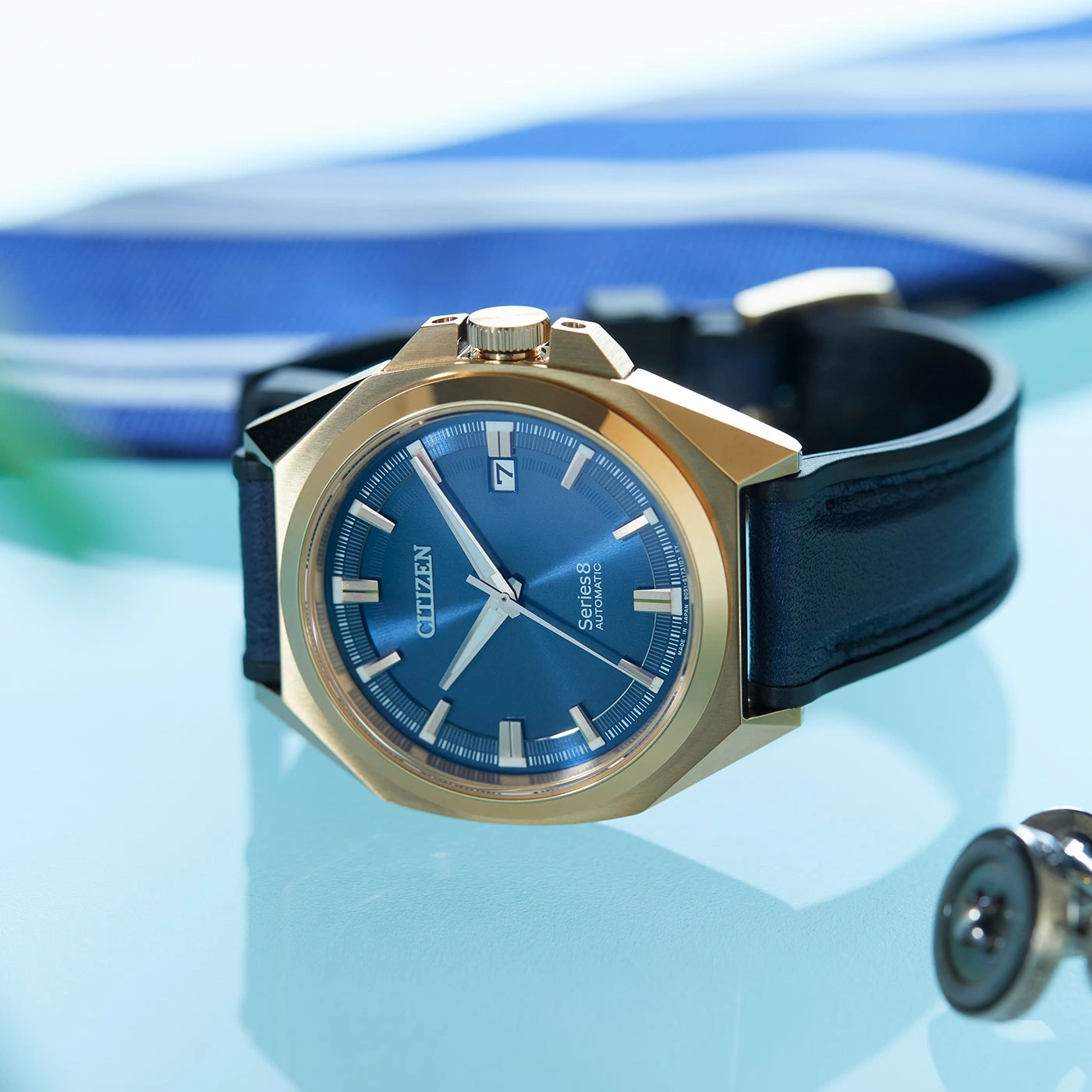 Close-up van een gouden horloge met een blauwe wijzerplaat en zwarte band.