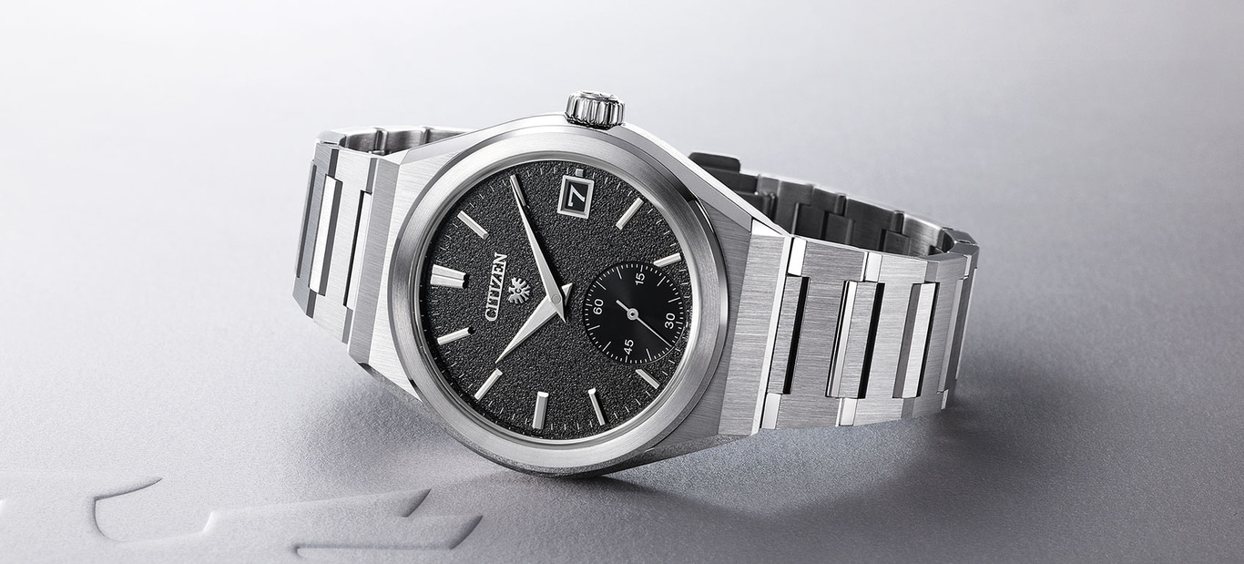 Citizen horloge met een zwarte textuur wijzerplaat en zilveren armband.