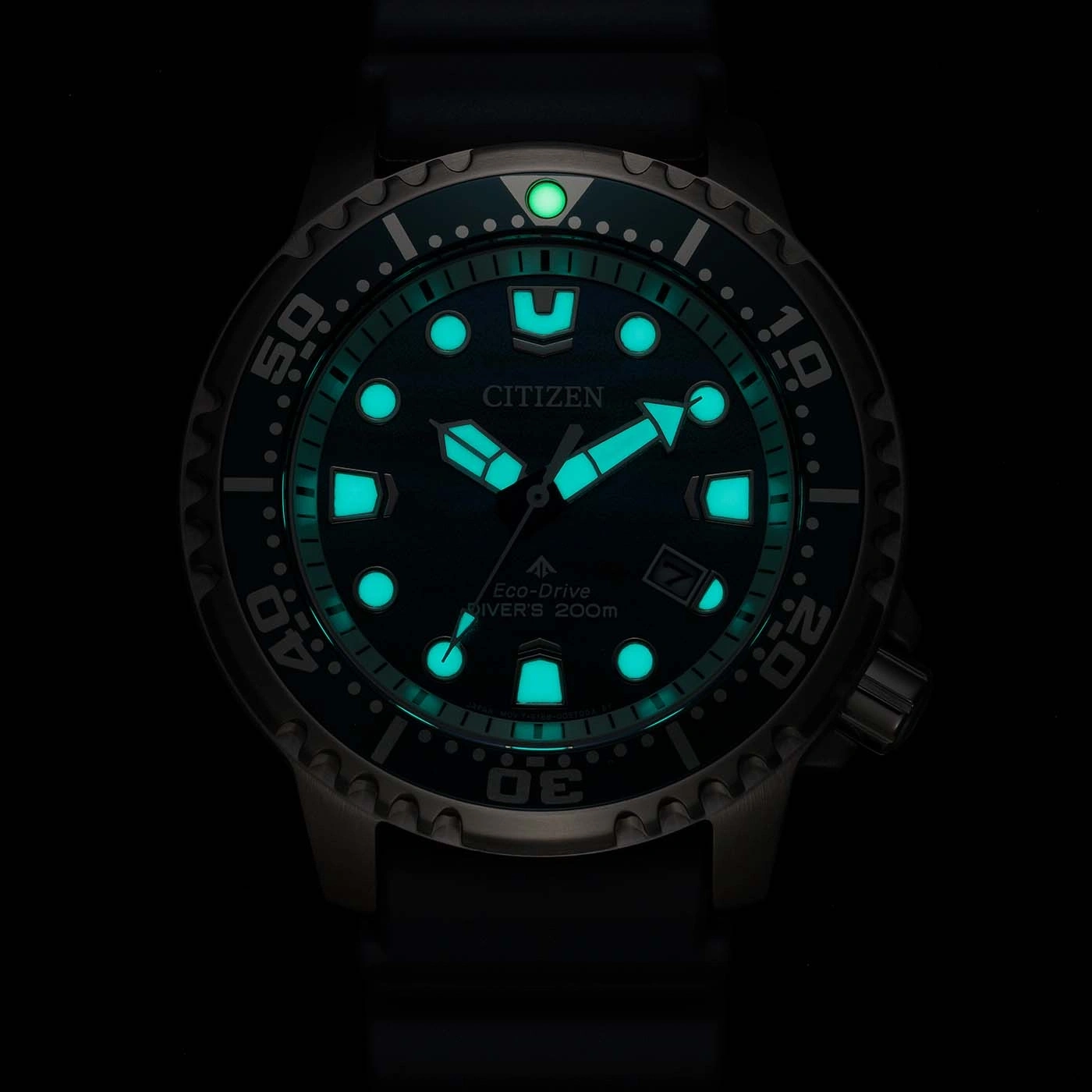 Een lichtgevend groen Citizen Eco-Drive duikhorloge gloeit in het donker.